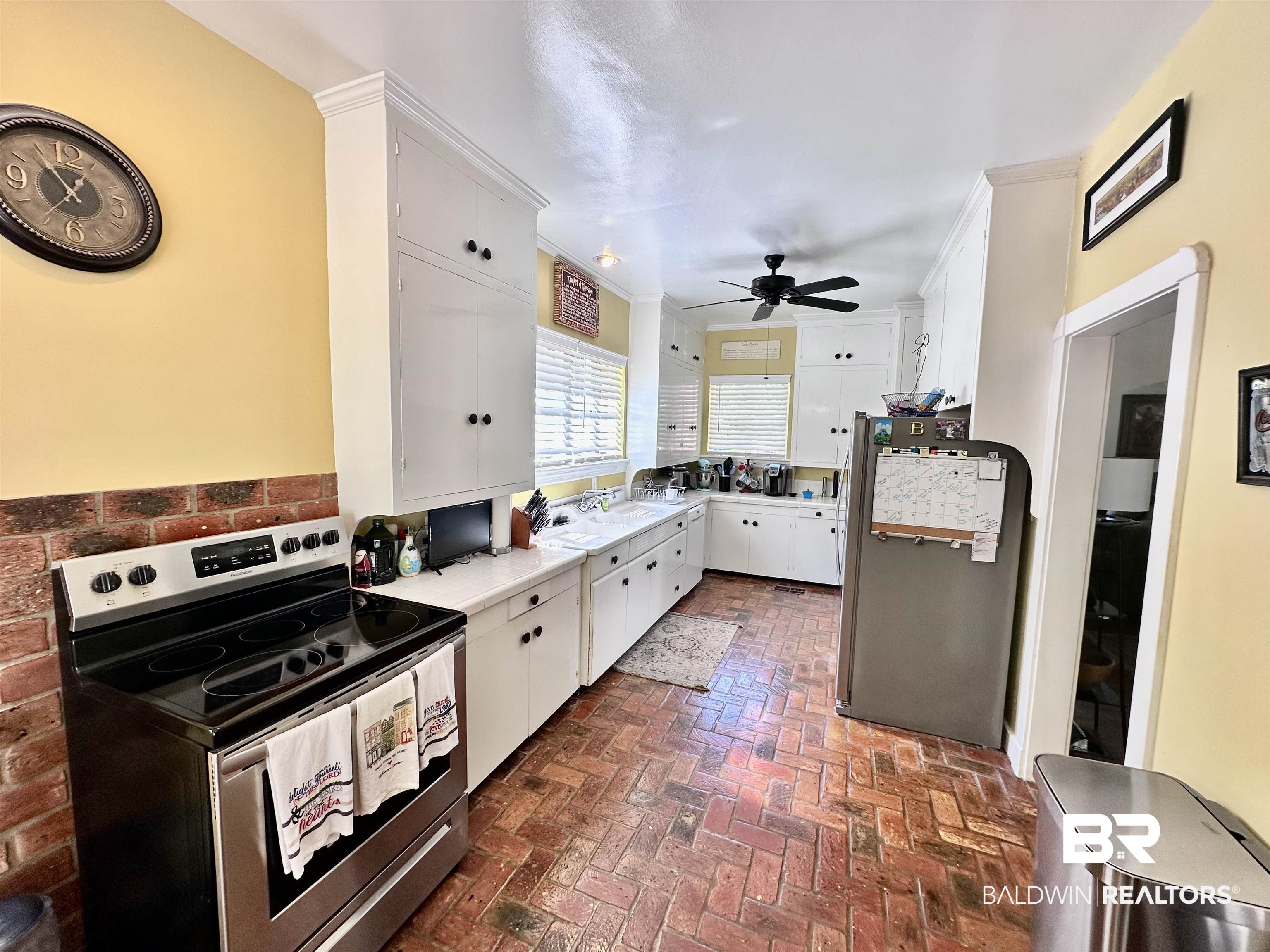 260 Siena Vista Street Mobile, AL 36607 - Photo 19 of 41 Kitchen with appliances with stainless steel finishes, brick floors, ceiling fan, white cabinets, and light countertops
