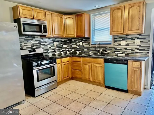 a kitchen with granite countertop a stove top oven microwave and cabinets