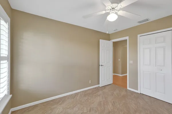 an empty room with windows and fan