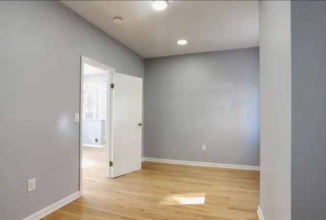 a view of an empty room with wooden floor and closet