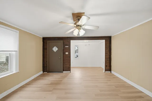a view of an empty room with window and a chandelier fan