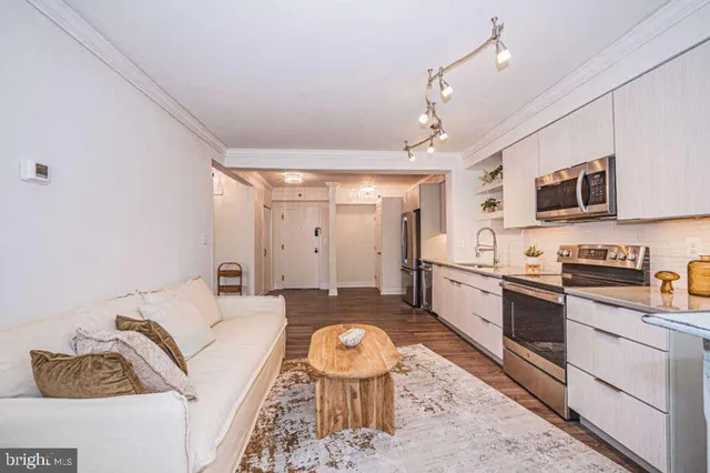 a large white kitchen with stainless steel appliances granite countertop a stove a sink dishwasher a dining table and chairs with wooden floor