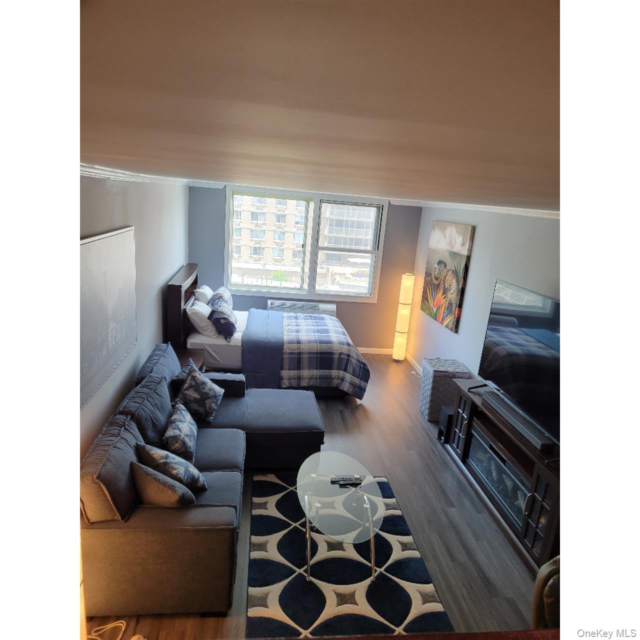 118-18 Union Turnpike, Unit 5J Queens, NY 11415 - Photo 21 of 24 a living room with furniture and a flat screen tv