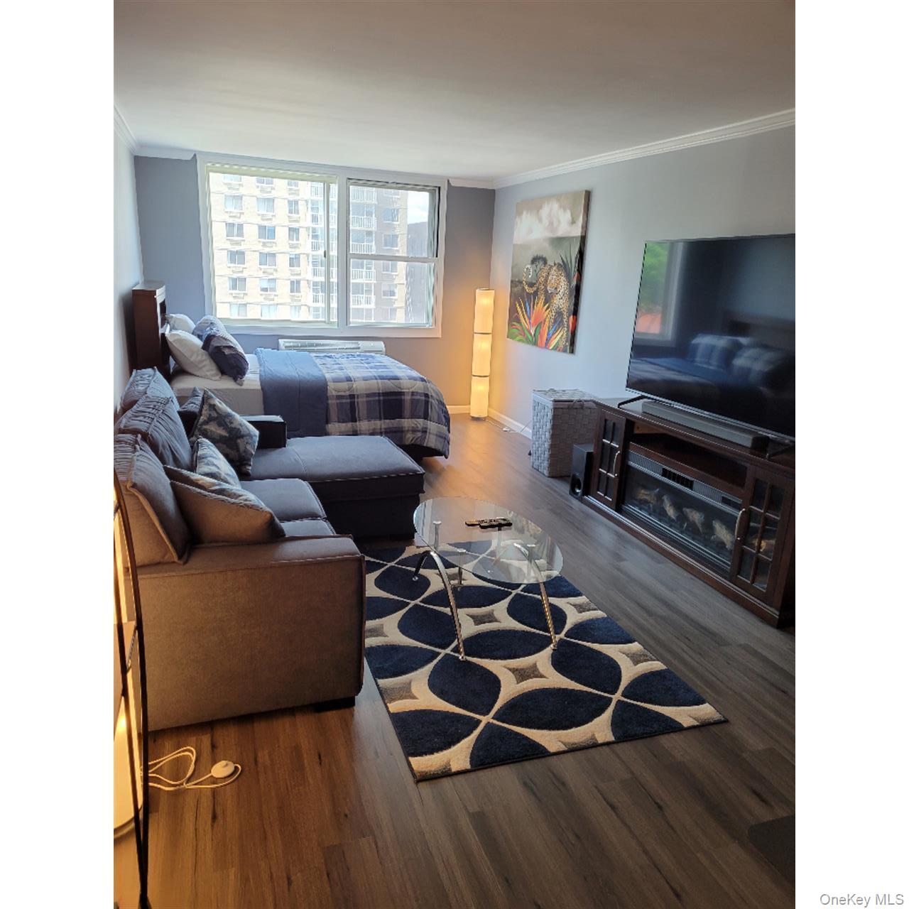 118-18 Union Turnpike, Unit 5J Queens, NY 11415 - Photo 9 of 24 a living room with furniture and a flat screen tv