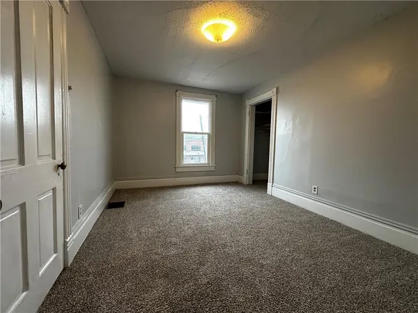 an empty room with windows and fireplace