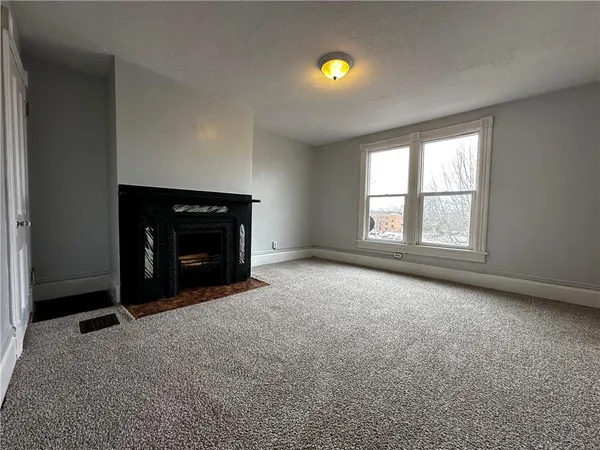 an empty room with a fireplace and window