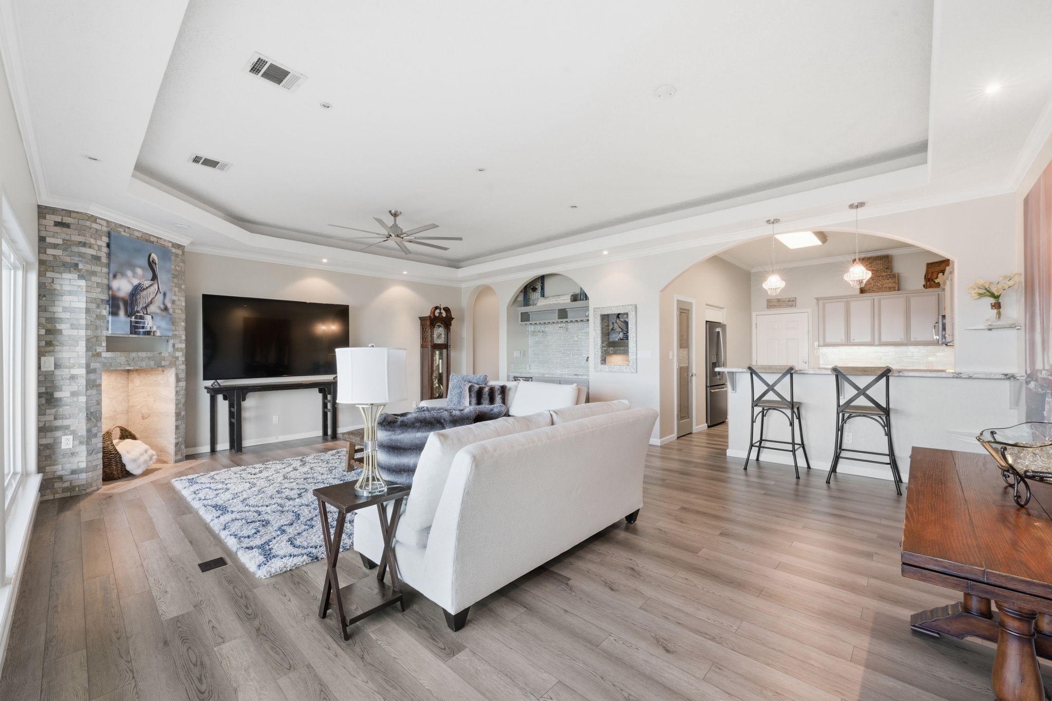 2 Regency Point Conroe, TX 77356 - Photo 9 of 44 Open-concept living and kitchen with tray ceilings, wood-look laminate waterproof flooring, breakfast bar, and stylish fireplace enclave for seamless everyday living and entertaining.