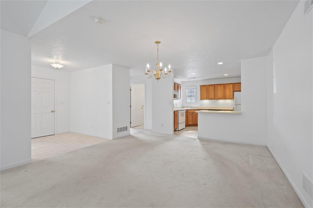 903 Hidden Meadows Circle Renfrew, PA 16053 - Photo 22 of 44 an empty room with a chandelier and a fireplace