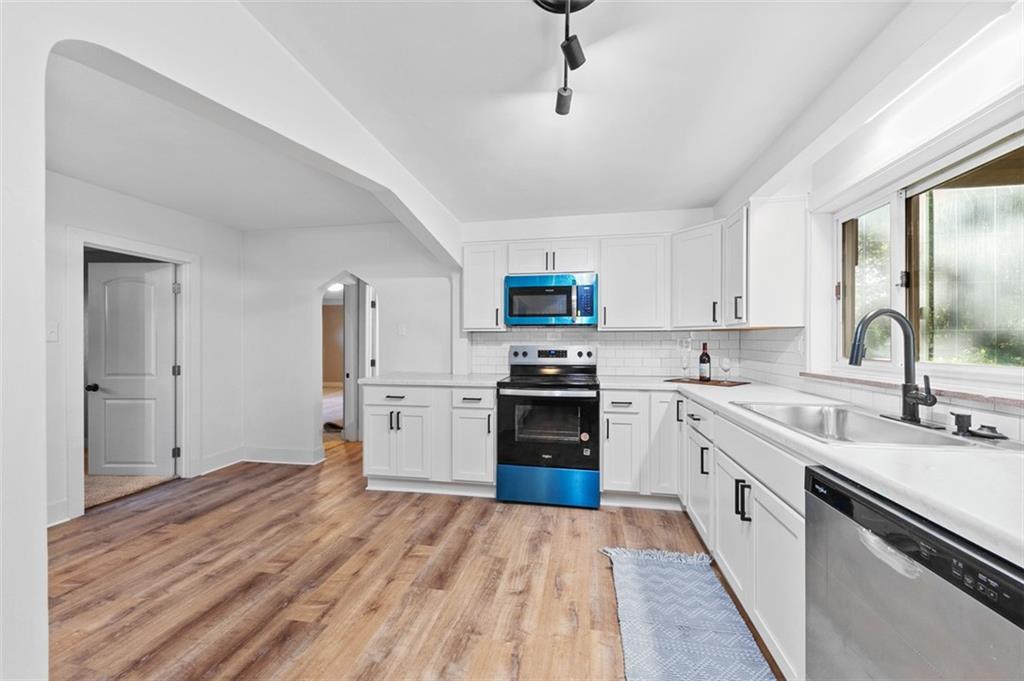 1812 Ridge Road Jeannette, PA 15644 - Photo 17 of 39 a kitchen with stainless steel appliances granite countertop a refrigerator a stove top oven a sink dishwasher and white cabinets with wooden floor
