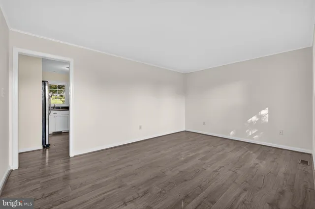 a view of an empty room with wooden floor and closet