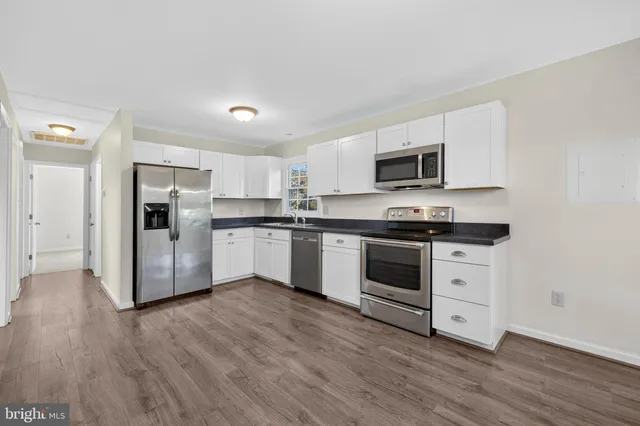a kitchen with granite countertop white cabinets and stainless steel appliances