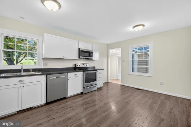 a kitchen with granite countertop a stove a sink and a microwave