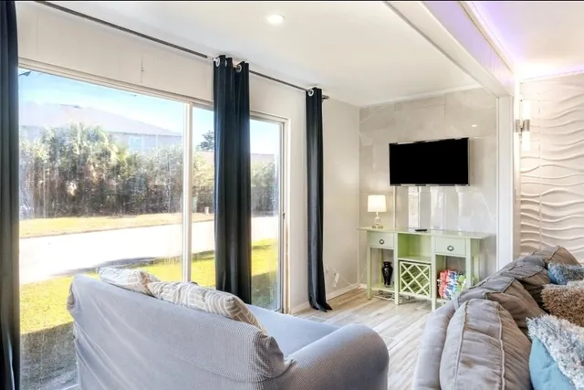 a living room with furniture a flat screen tv and a floor to ceiling window