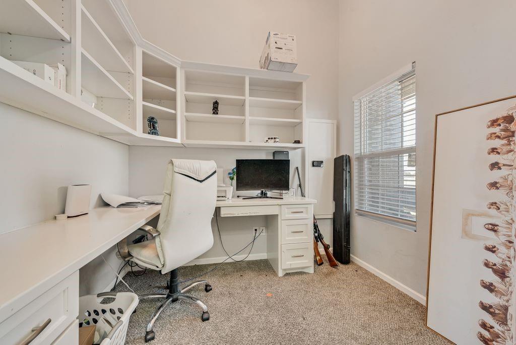 610 Ewing Road Ferris, TX 75125 - Photo 7 of 22 Built-in shelving, integrated desk, window with blinds, and neutral carpeting