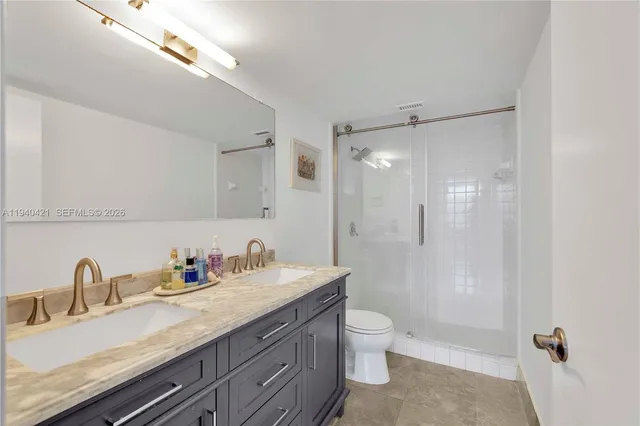 a bathroom with a granite countertop sink a toilet and shower
