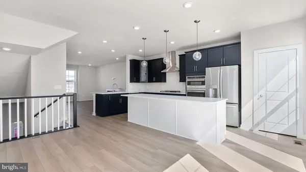 a large white kitchen with a refrigerator a stove top oven and a sink