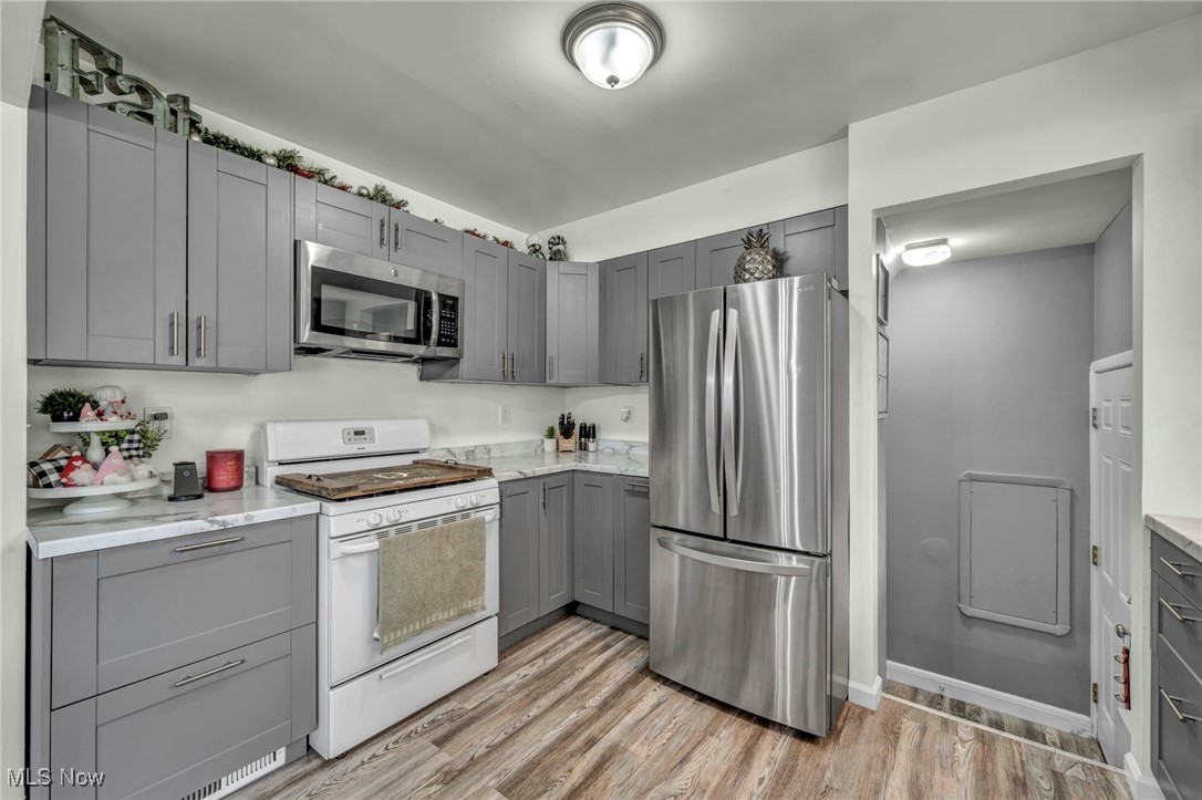15025 Holland Road Brook Park, OH 44142 - Photo 3 of 12 Kitchen featuring appliances with stainless steel finishes, gray cabinets, light wood-style flooring, and light stone countertops