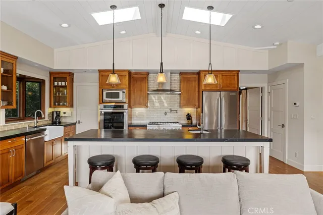 a kitchen with stainless steel appliances granite countertop a stove a sink and a refrigerator with wooden floor