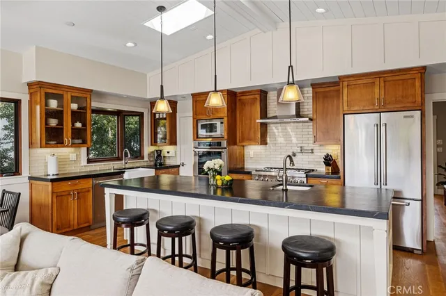 a kitchen with stainless steel appliances granite countertop a refrigerator a sink a stove and chairs