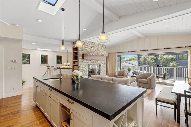 a large kitchen with stainless steel appliances granite countertop a sink a stove and a dining table with the view of living room