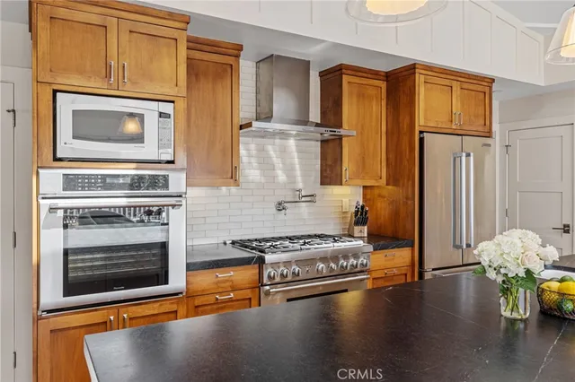 a kitchen with stainless steel appliances a stove a refrigerator and a fireplace with wooden floor