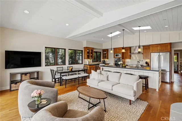 a living room with furniture kitchen view and a large window