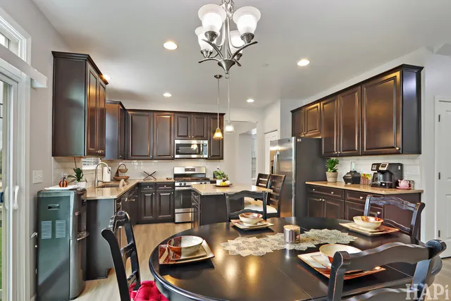 a kitchen with a refrigerator a stove top oven a sink dishwasher and dining table with wooden floor