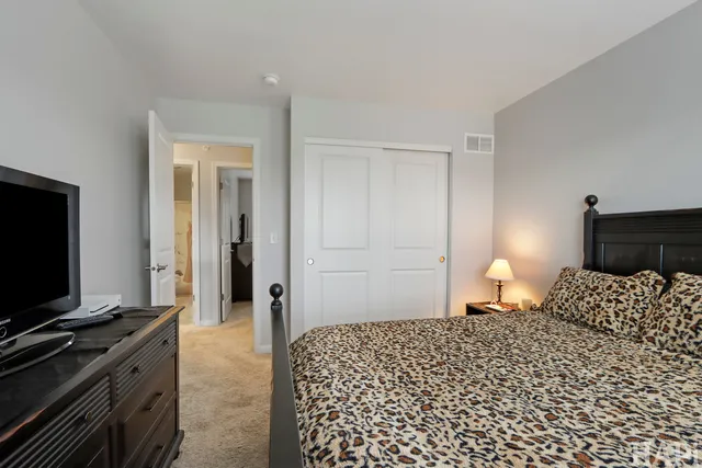 a bedroom with a bed and a flat tv screen on a dresser