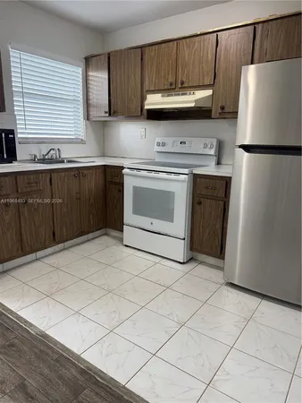 a kitchen with granite countertop a refrigerator sink and cabinets