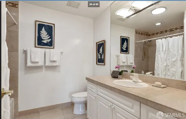 a bathroom with a granite countertop sink mirror vanity and toilet