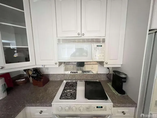 a kitchen with a stove and white cabinets