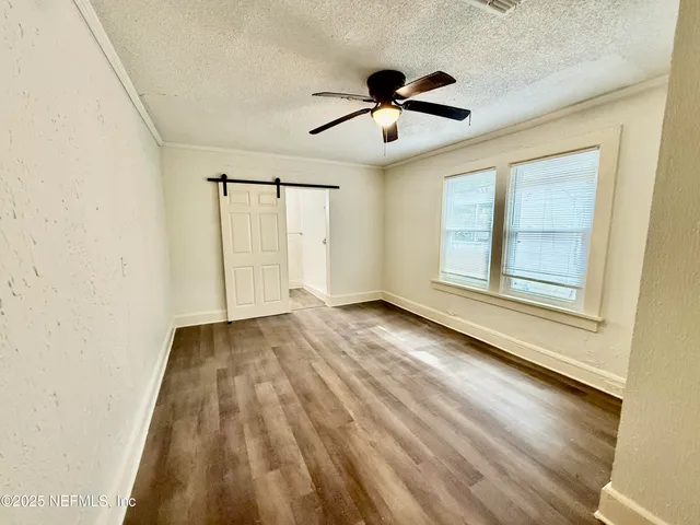 a view of empty room with wooden floor and fan