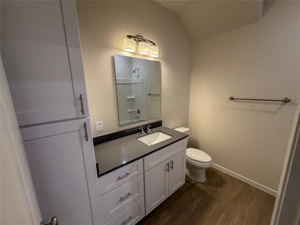 a bathroom with a granite countertop toilet sink and mirror