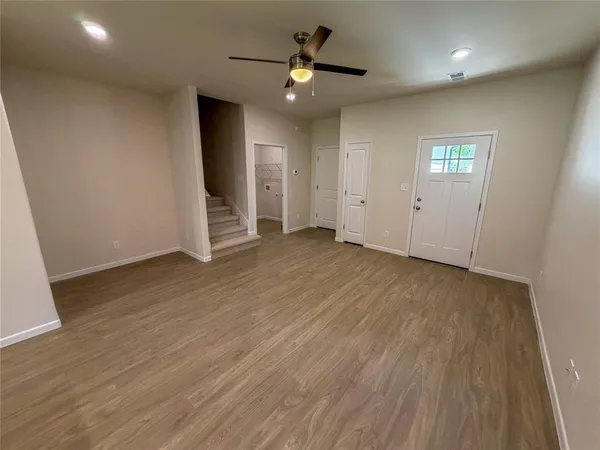 an empty room with wooden floor and a ceiling fan
