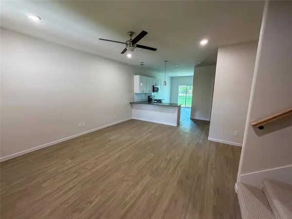 an empty room with wooden floor a ceiling fan and windows