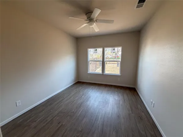 an empty room with wooden floor chandelier and windows