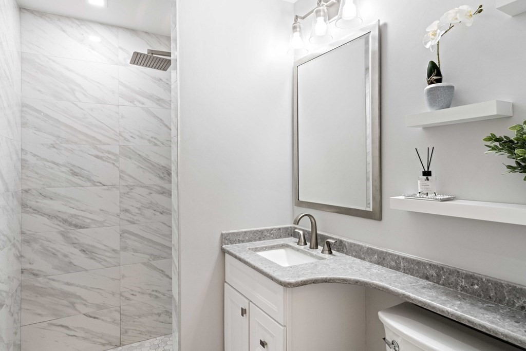 226 Commonwealth Avenue, Unit 1 Boston, MA 02116 - Photo 9 of 17 a bathroom with a granite countertop sink and a mirror
