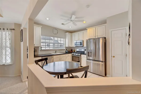 a kitchen with stainless steel appliances granite countertop a refrigerator a sink a stove a dining table and chairs
