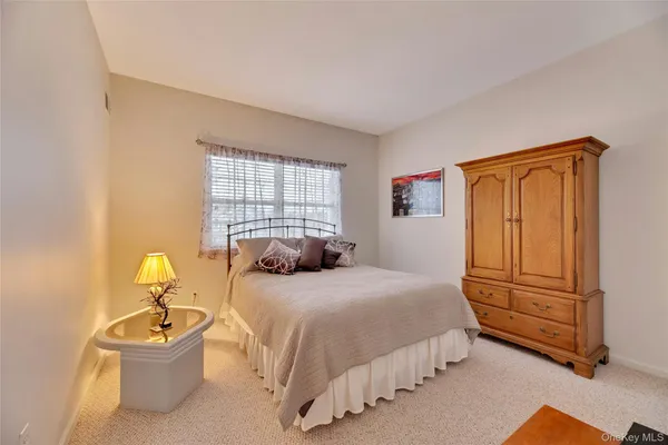a bedroom with a bed and dresser with wooden floor