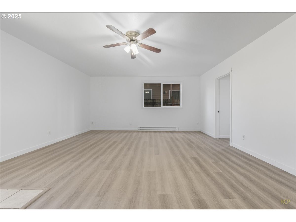 11420 Southeast Clinton Street Portland, OR 97266 - Photo 11 of 34 an empty room with wooden floor chandelier fan and windows