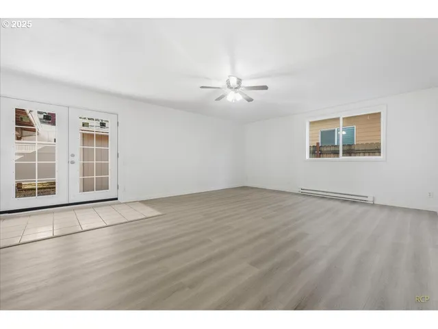 a view of an empty room with a window and wooden floor