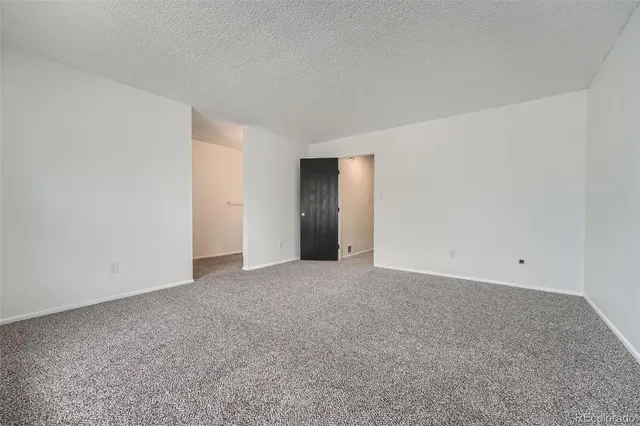 a view of an empty room with closet and entryway
