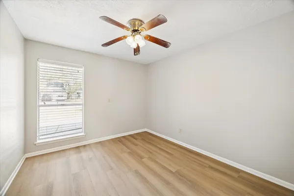 an empty room with a window and ceiling fan
