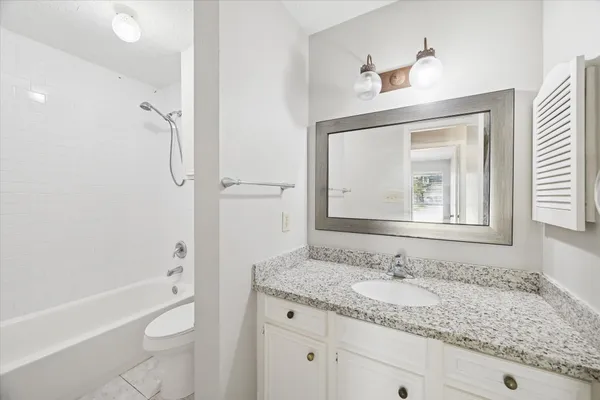 a bathroom with a granite countertop sink toilet and shower