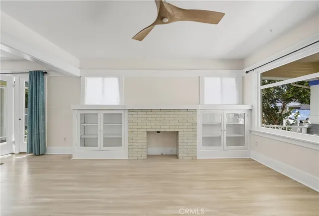 an empty room with wooden floor fireplace and windows
