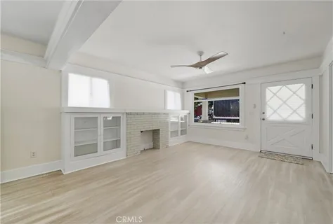 an empty room with wooden floor cabinet and windows