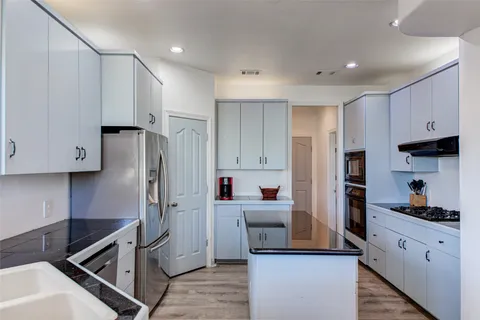 a kitchen with stainless steel appliances kitchen island granite countertop a refrigerator and a stove top oven