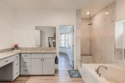 a spacious bathroom with a granite countertop sink a mirror a bathtub and shower