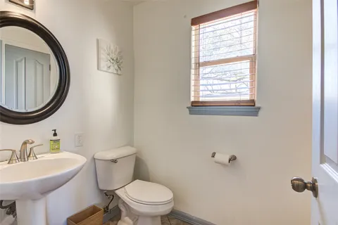 a bathroom with a sink a toilet mirror and a window