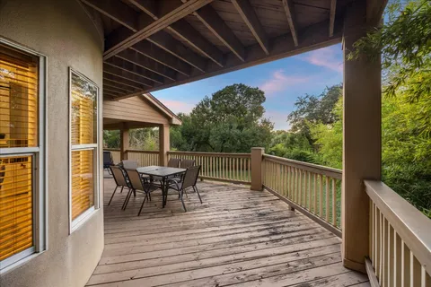a balcony with wooden floor table and chairs